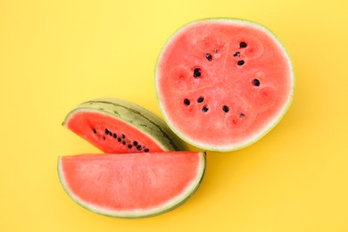 Delicious cut ripe watermelons on yellow background, flat lay