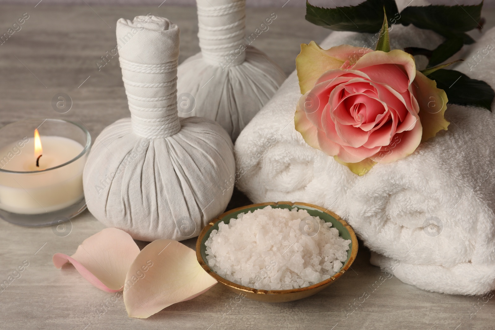 Photo of Composition with spa products, rose and candle on grey wooden table, closeup