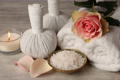 Photo of Composition with spa products, rose and candle on grey wooden table, closeup