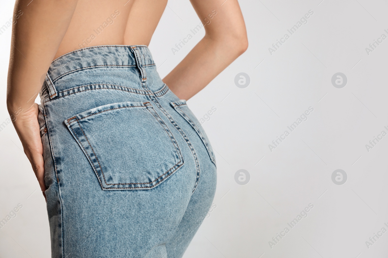 Photo of Woman in stylish jeans on light background, closeup. Space for text