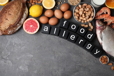 Flat lay composition of different products and black cubes with words Food Allergy on grey table, space for text