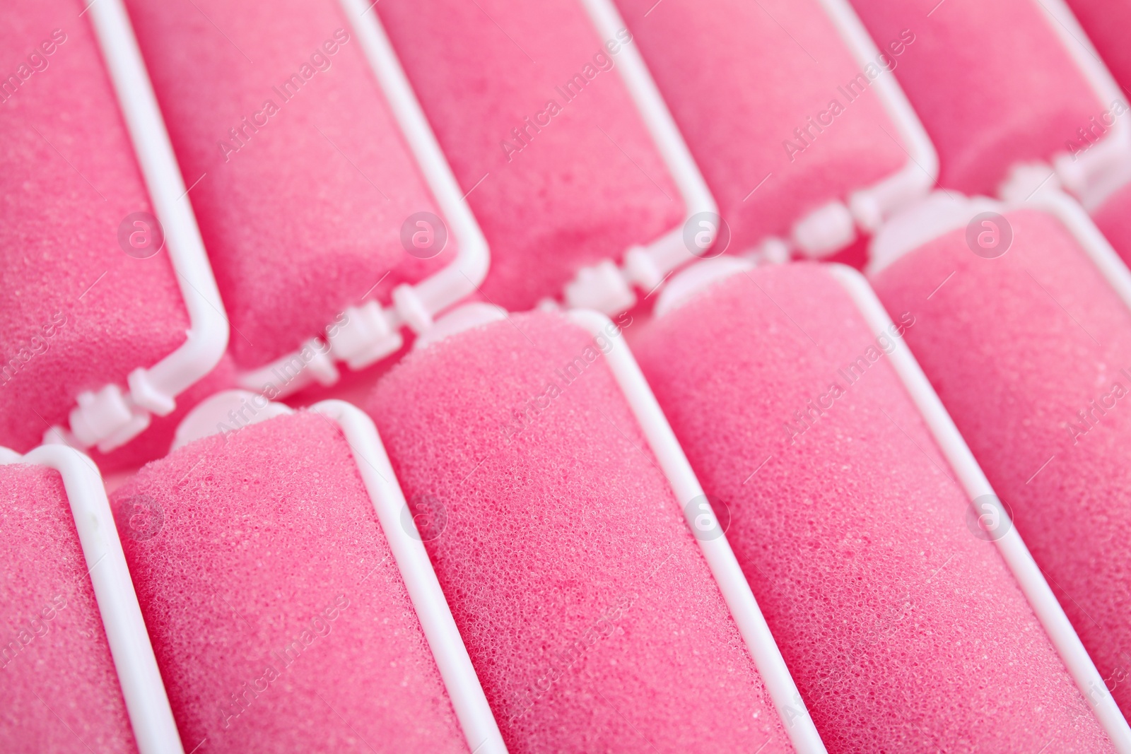 Photo of Many pink hair curlers as background, closeup