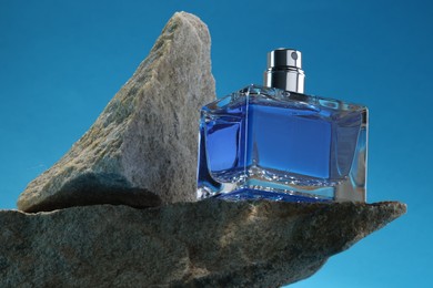 Stylish presentation of luxury men`s perfume on stones against light blue background