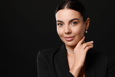 Photo of Young woman with elegant pearl jewelry on black background, space for text