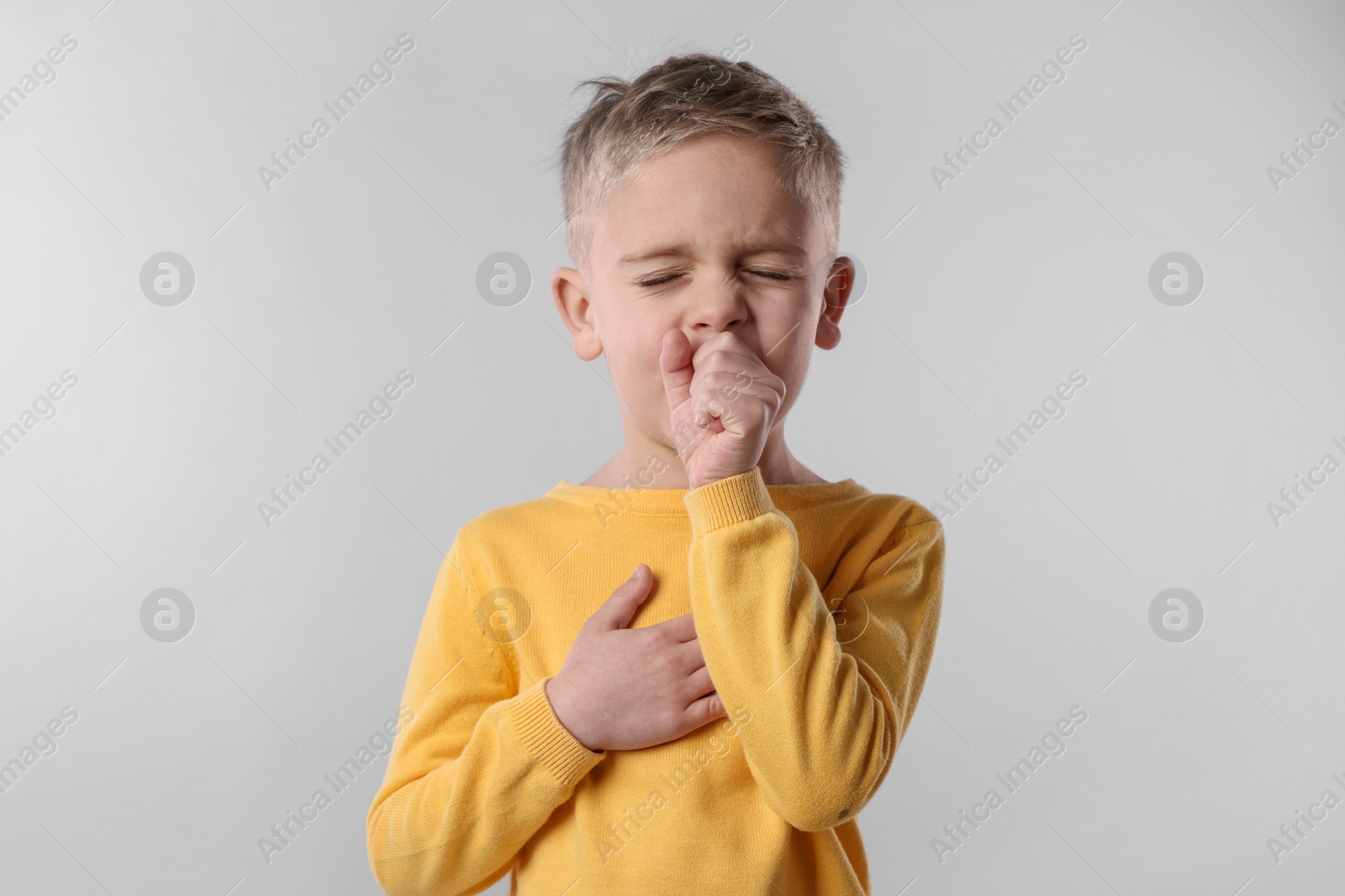 Photo of Sick boy coughing on gray background. Cold symptoms