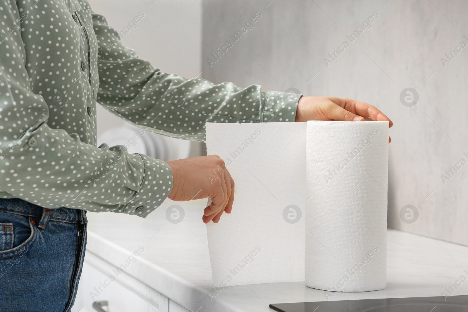 Photo of Woman tearing paper towels in kitchen, closeup