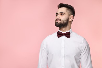 Portrait of smiling man in shirt and bow tie on pink background. Space for text