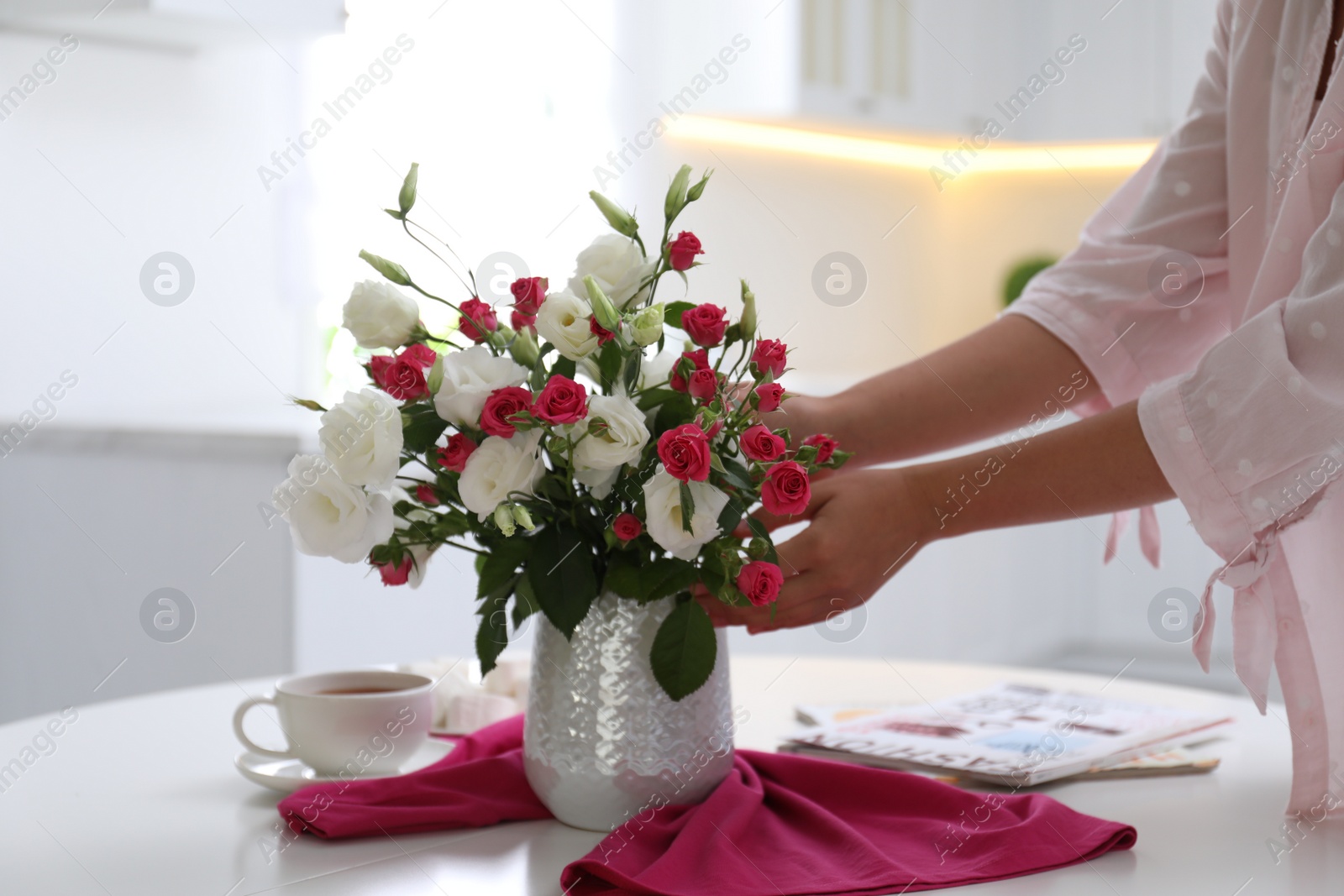 Photo of Woman with bouquet of fresh flowers in stylish vase at table, closeup