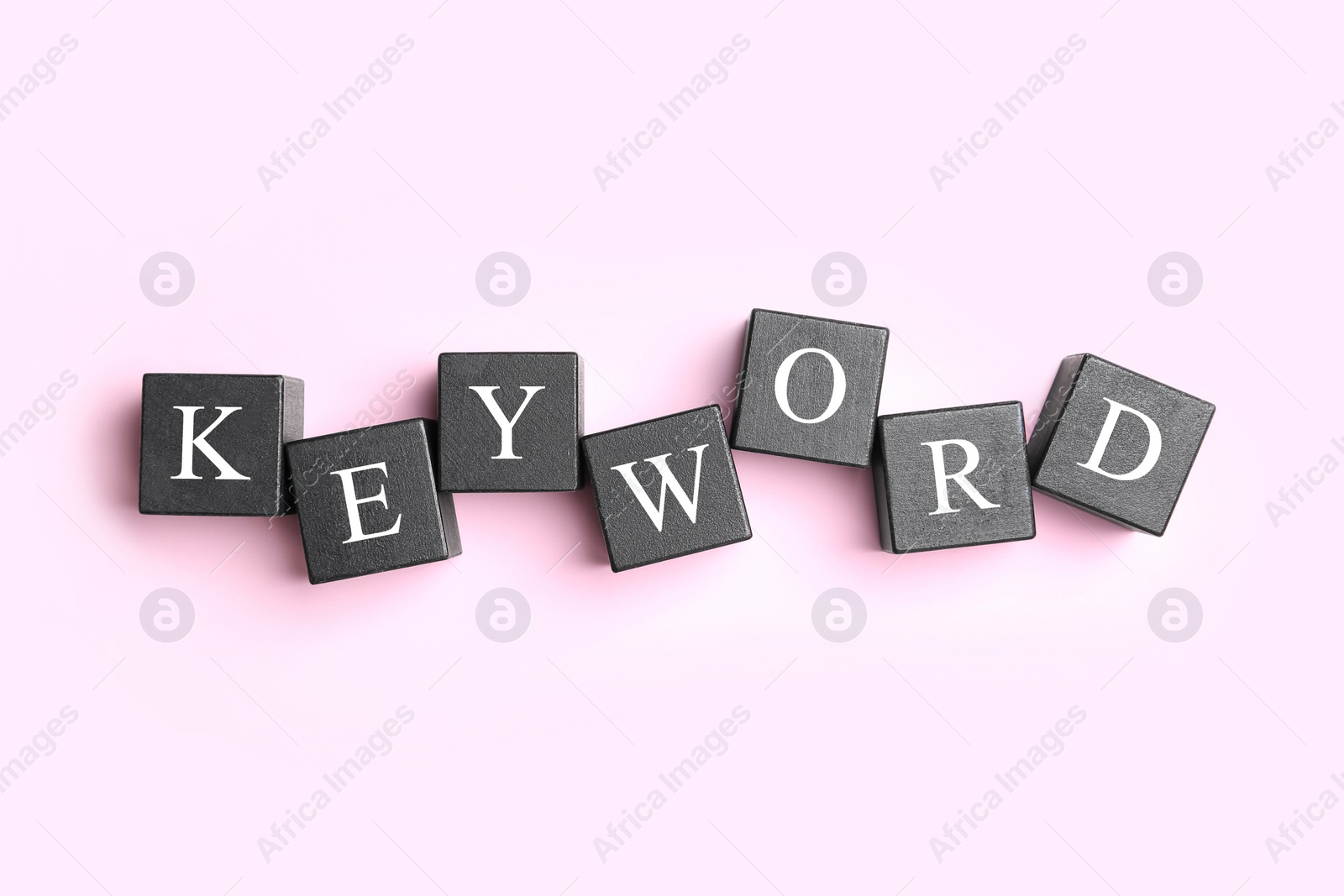 Photo of Black cubes with word KEYWORD on pink background, flat lay