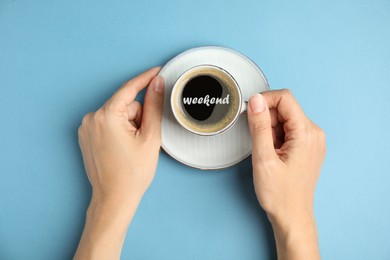 Image of Happy Weekend. Woman with cup of hot aromatic espresso on light blue background, top view