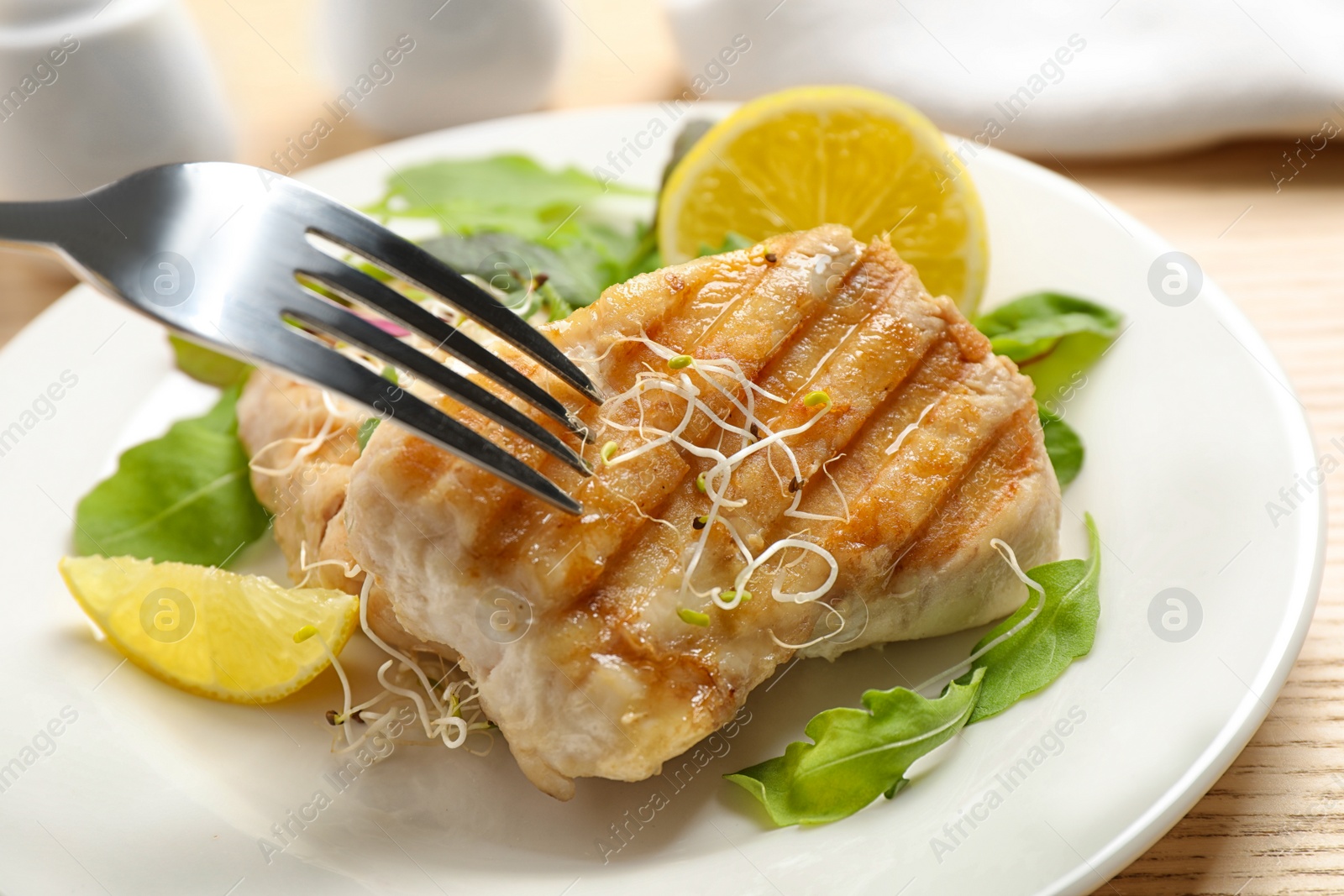 Photo of Tasty grilled fish served on wooden table, closeup