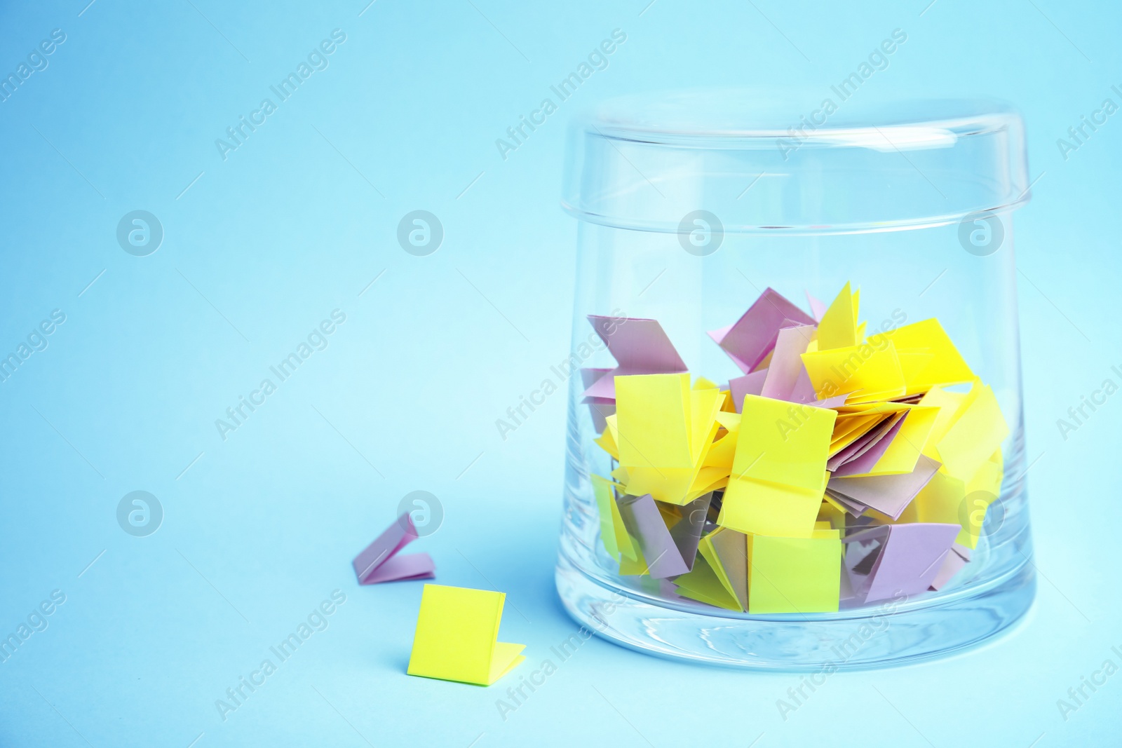 Photo of Glass container and paper pieces for lottery on color background. Space for text