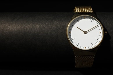 Stylish golden wristwatch on black background, closeup. Space for text