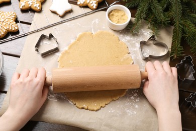 Photo of Making Christmas cookies. Woman rolling raw dough at wooden table, top view