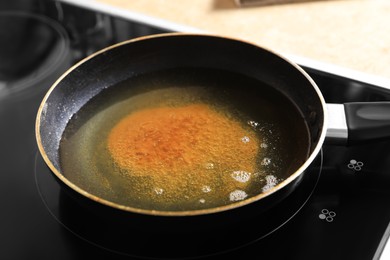 Photo of Frying pan with used cooking oil on stove, closeup
