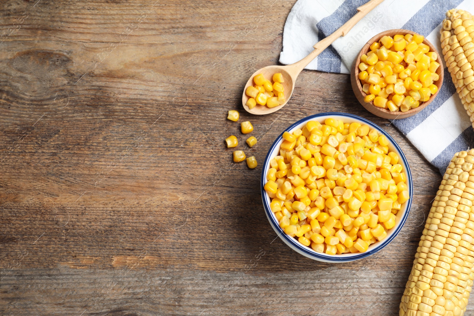 Photo of Delicious canned corn in bowl on wooden table, flat lay. Space for text