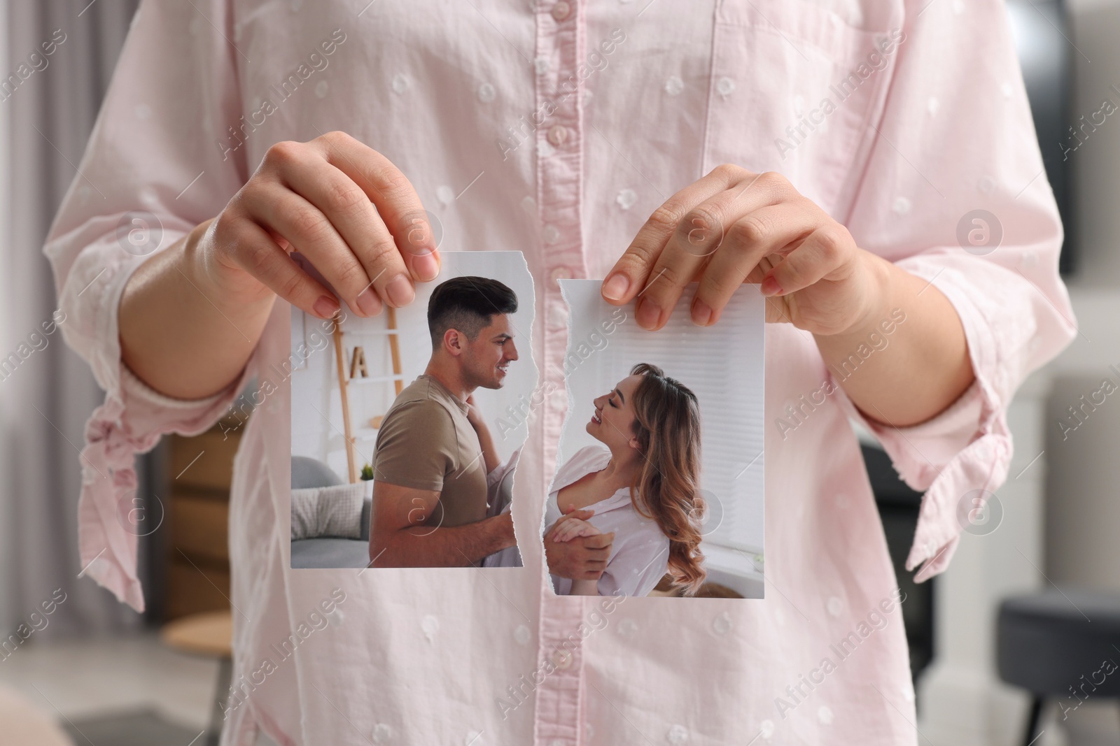 Photo of Woman holding torn photo in room, closeup. Divorce concept