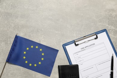 Photo of Visa application form, passport, pen and small flag of European Union on light grey table, flat lay. Space for text
