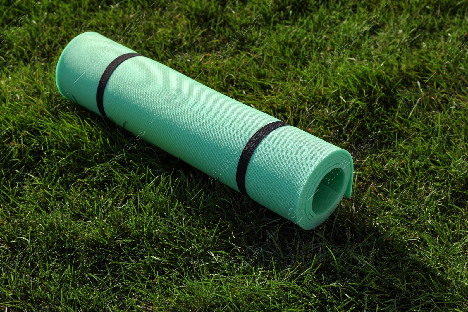 Photo of Bright exercise mat on fresh green grass outdoors