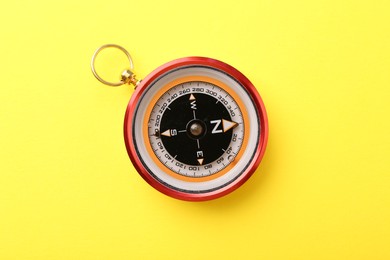 Photo of Compass on yellow background, top view. Navigation equipment