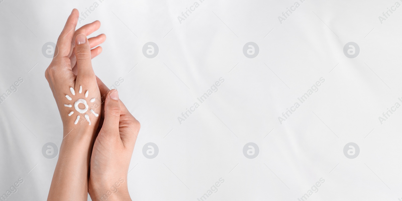 Image of Sun painted with cream on hands against white background, closeup view with space for text. Banner design