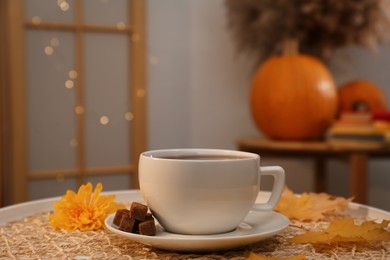 Photo of Cup of aromatic tea with sugar, flower and autumn leaves on white table in room, space for text