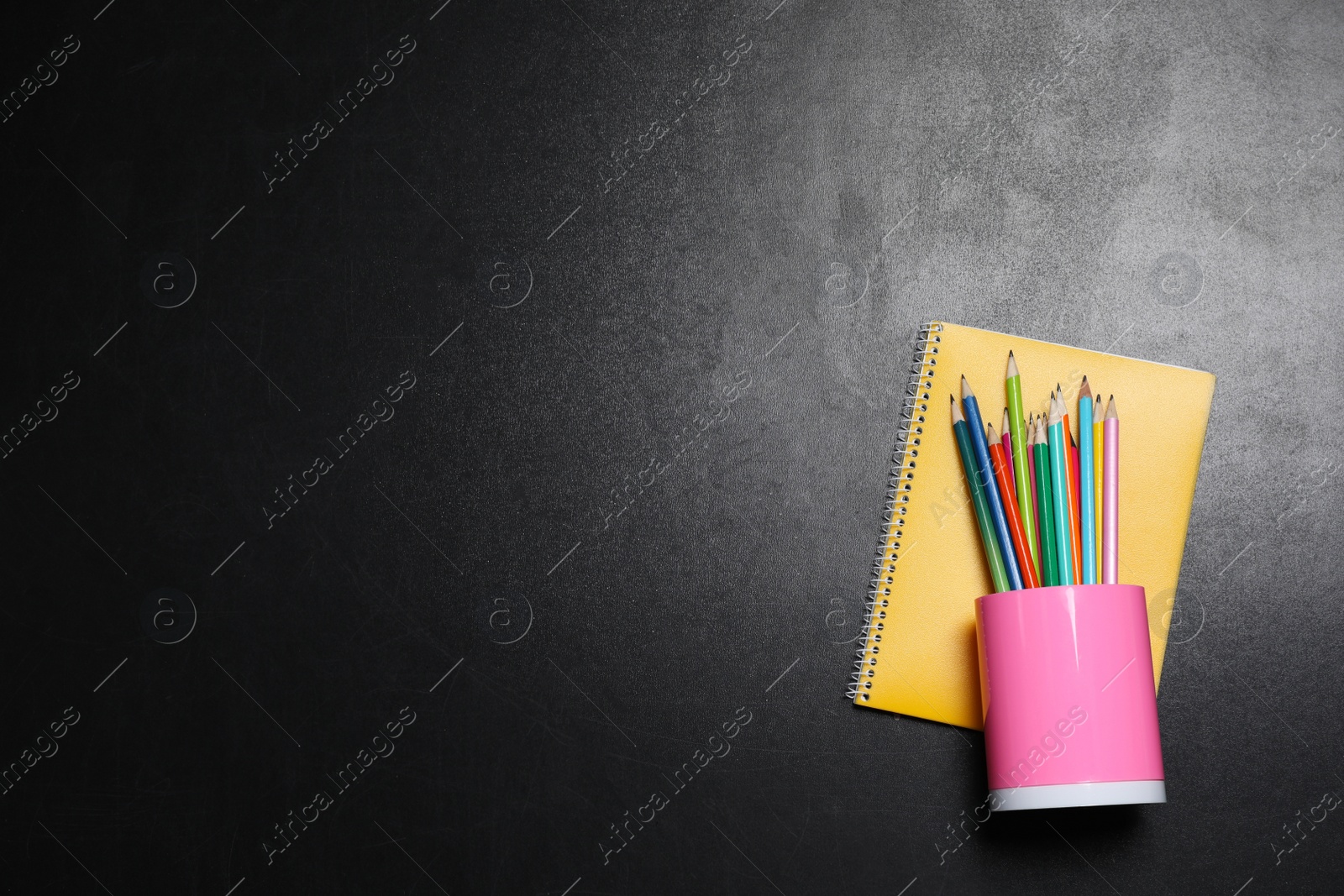 Photo of Pencils, notebook on blackboard with flowers drawing, flat lay. Space for text