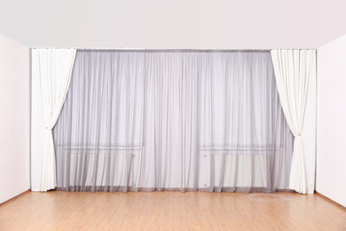 Windows with elegant curtains and blinds in empty room