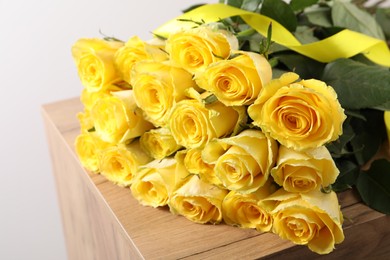 Photo of Beautiful bouquet of yellow roses on wooden table, closeup