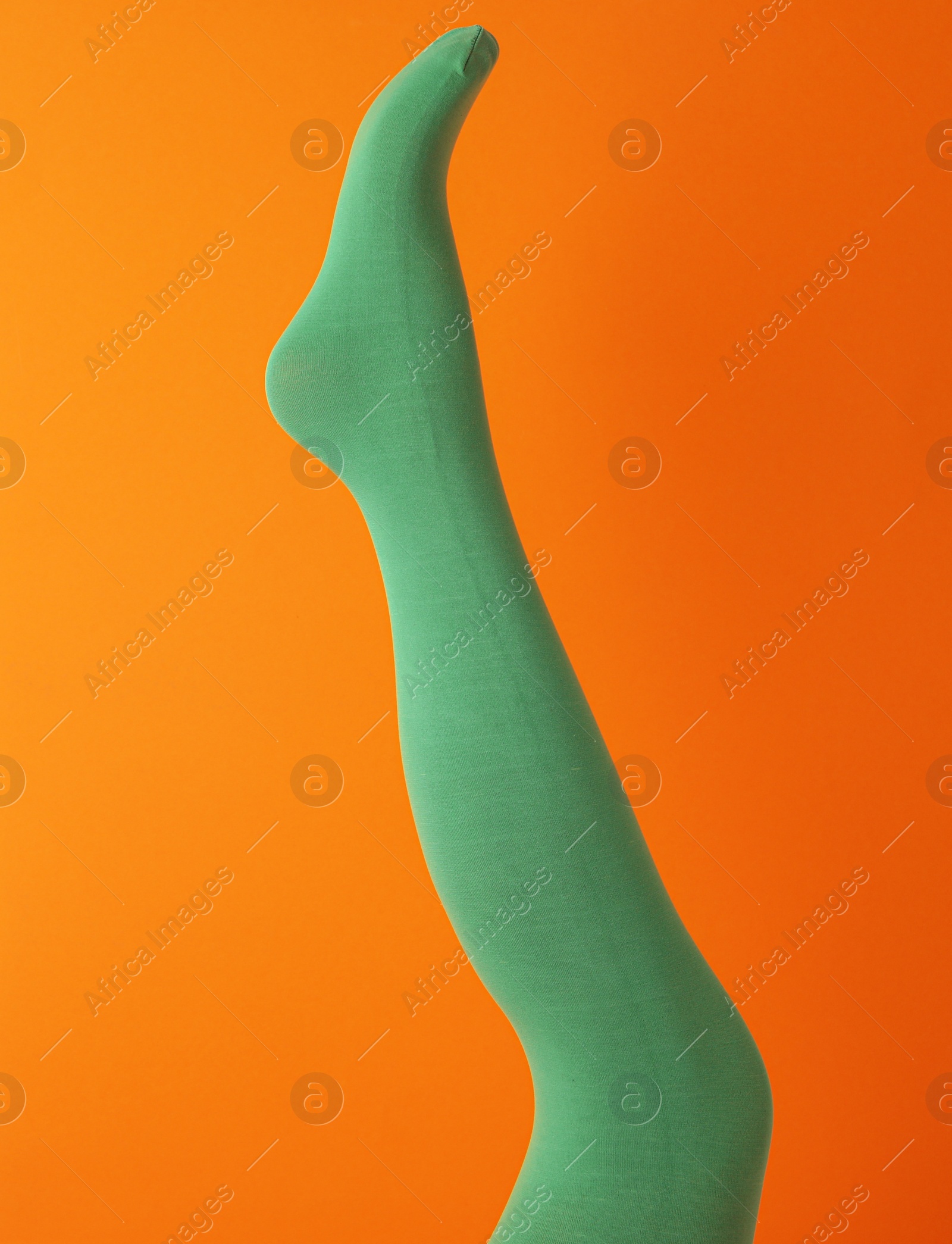 Photo of Leg mannequin in green tights on orange background