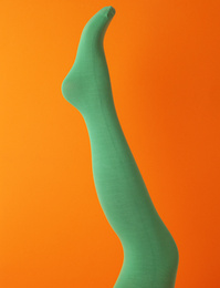 Photo of Leg mannequin in green tights on orange background