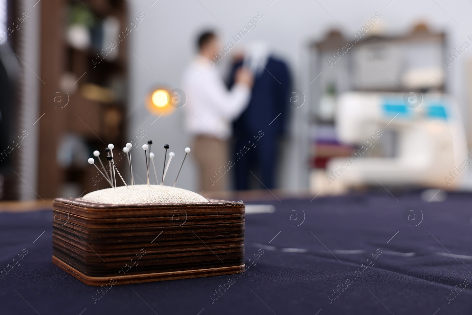 Photo of Dressmaker working in atelier, focus on pin cushion. Space for text