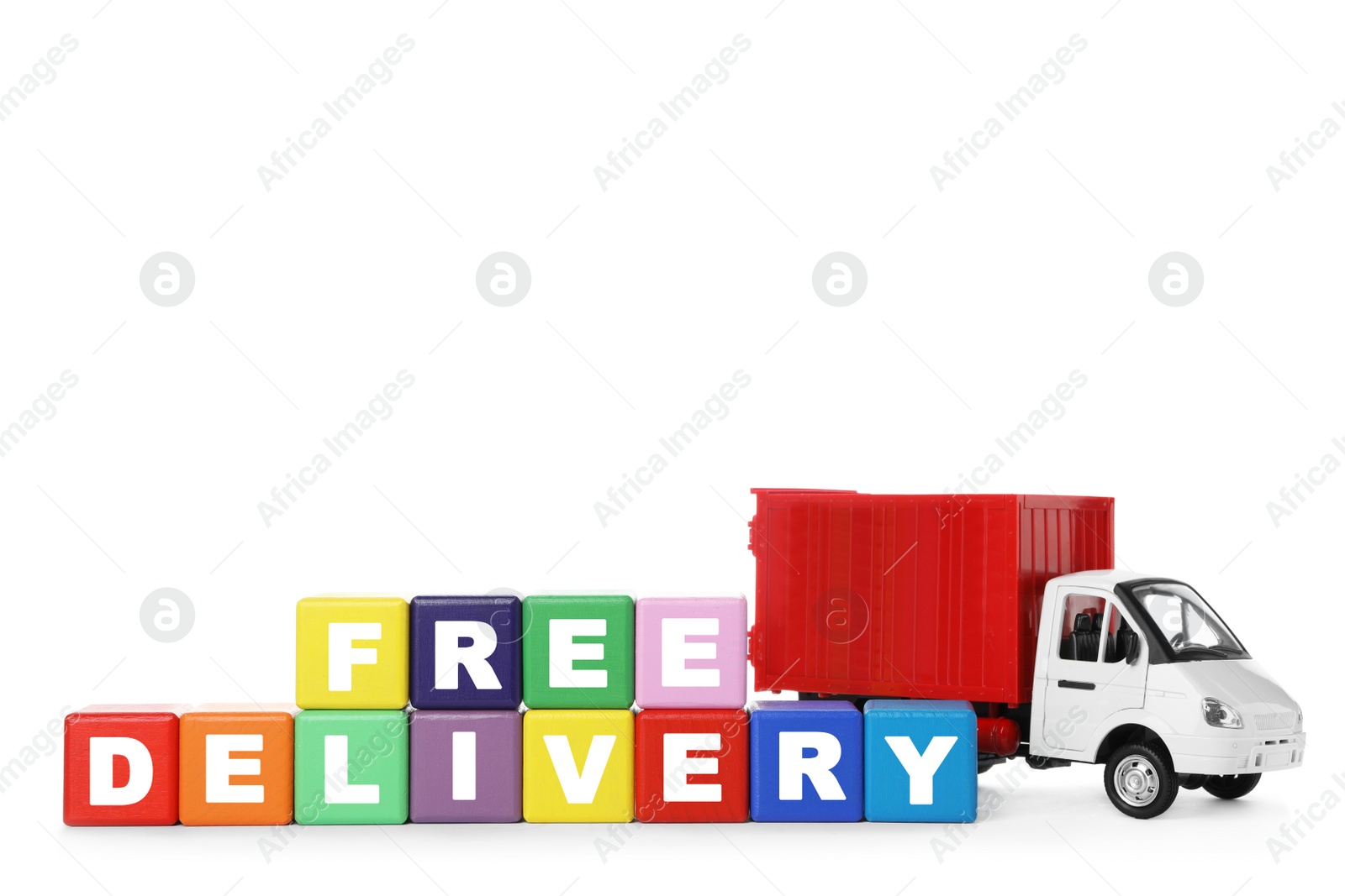 Photo of Toy truck and cubes with words FREE DELIVERY isolated on white. Logistics and wholesale concept