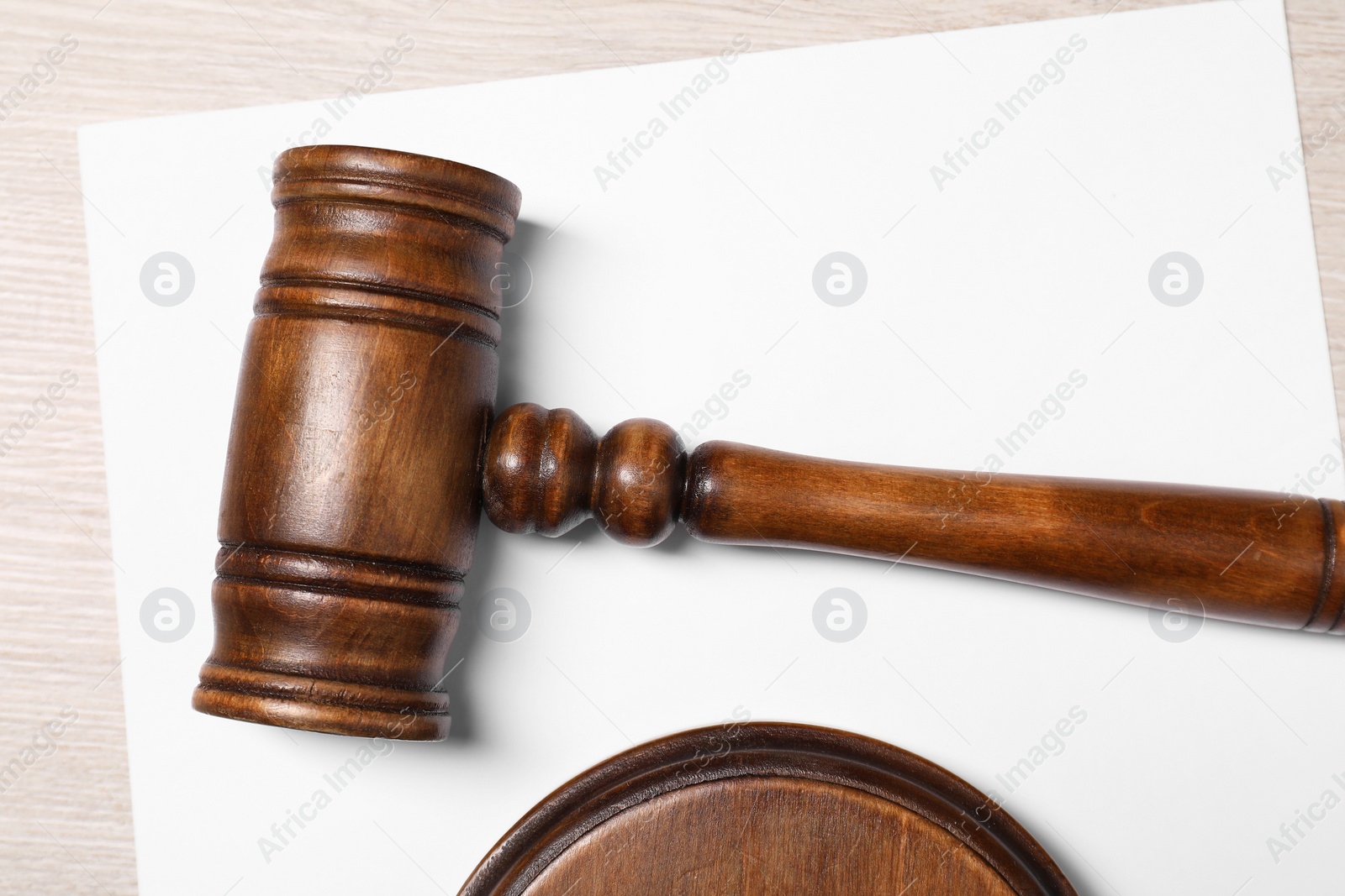 Photo of Gavel and sheet of paper on light wooden table, top view