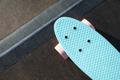 Photo of Modern light blue skateboard with pink wheels on ramp outdoors, top view. Space for text