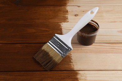 Photo of Wood stain in plastic container and brush on wooden surface