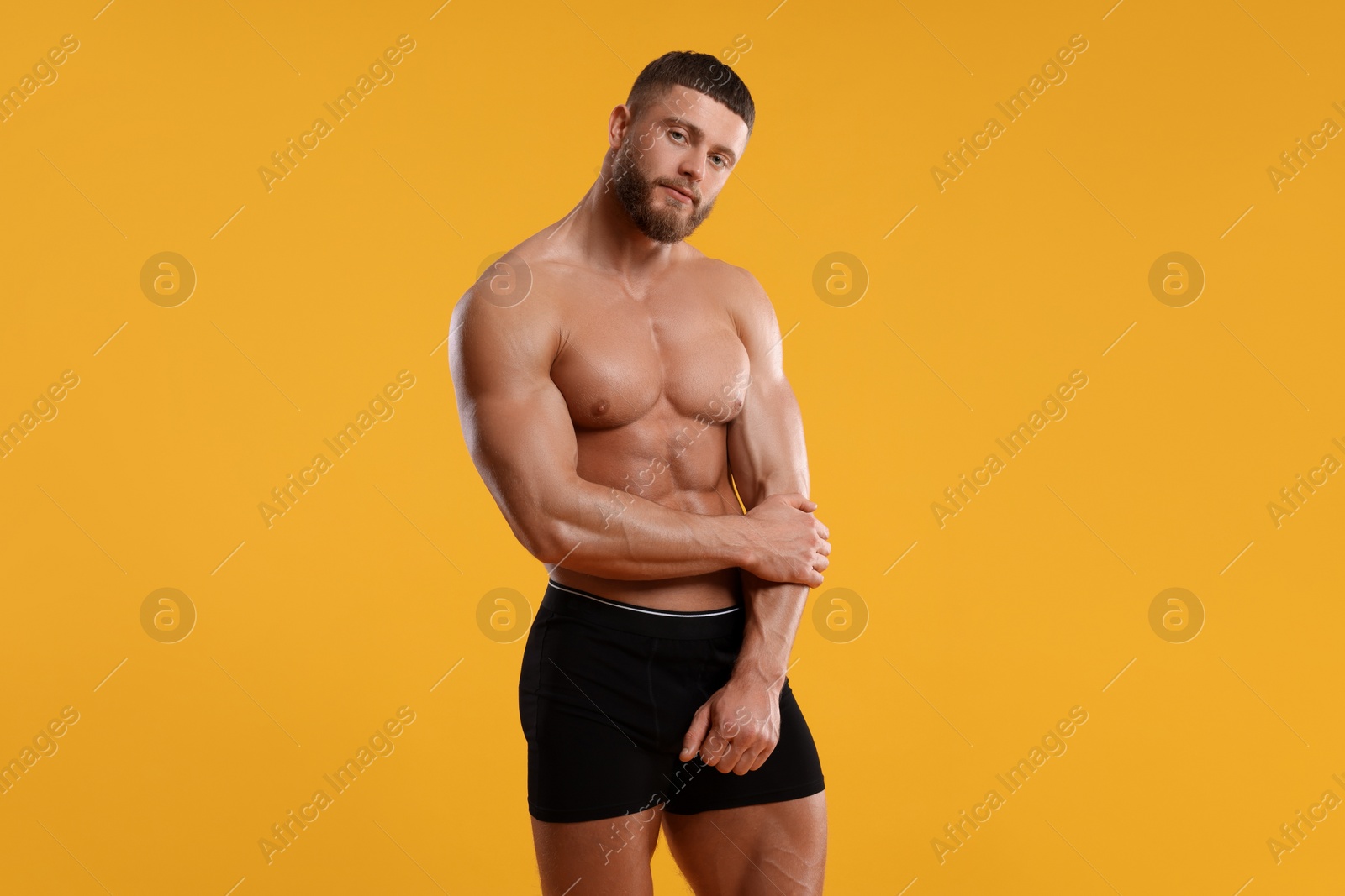 Photo of Young man is stylish black underwear on orange background