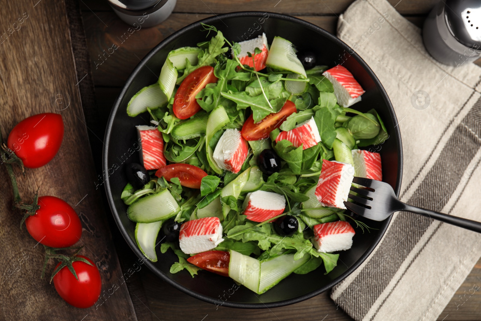 Photo of Delicious crab stick salad served on wooden table, flat lay