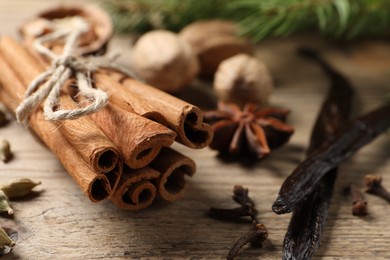 Photo of Cinnamon sticks and other spices on wooden table, closeup