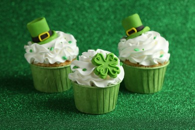 St. Patrick's day party. Tasty festively decorated cupcakes on shiny green surface, closeup