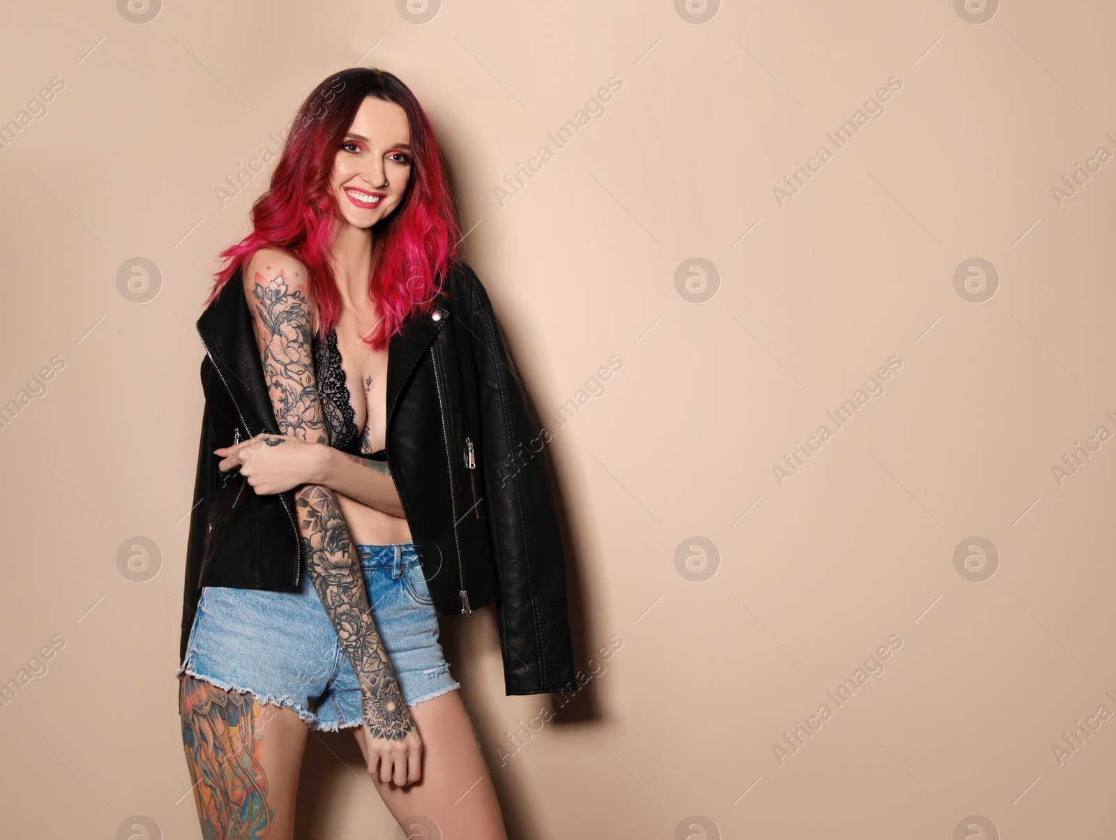 Photo of Beautiful woman with tattoos on body against beige background. Space for text