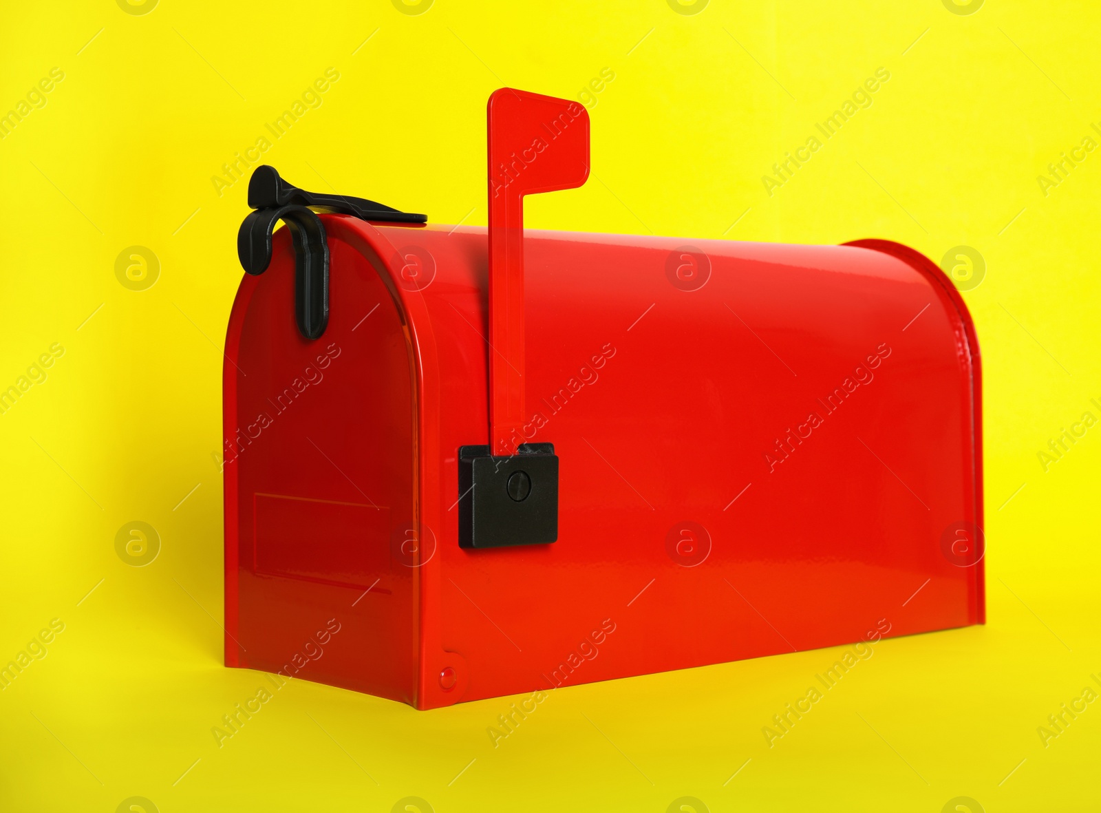 Photo of Closed red letter box on yellow background, closeup