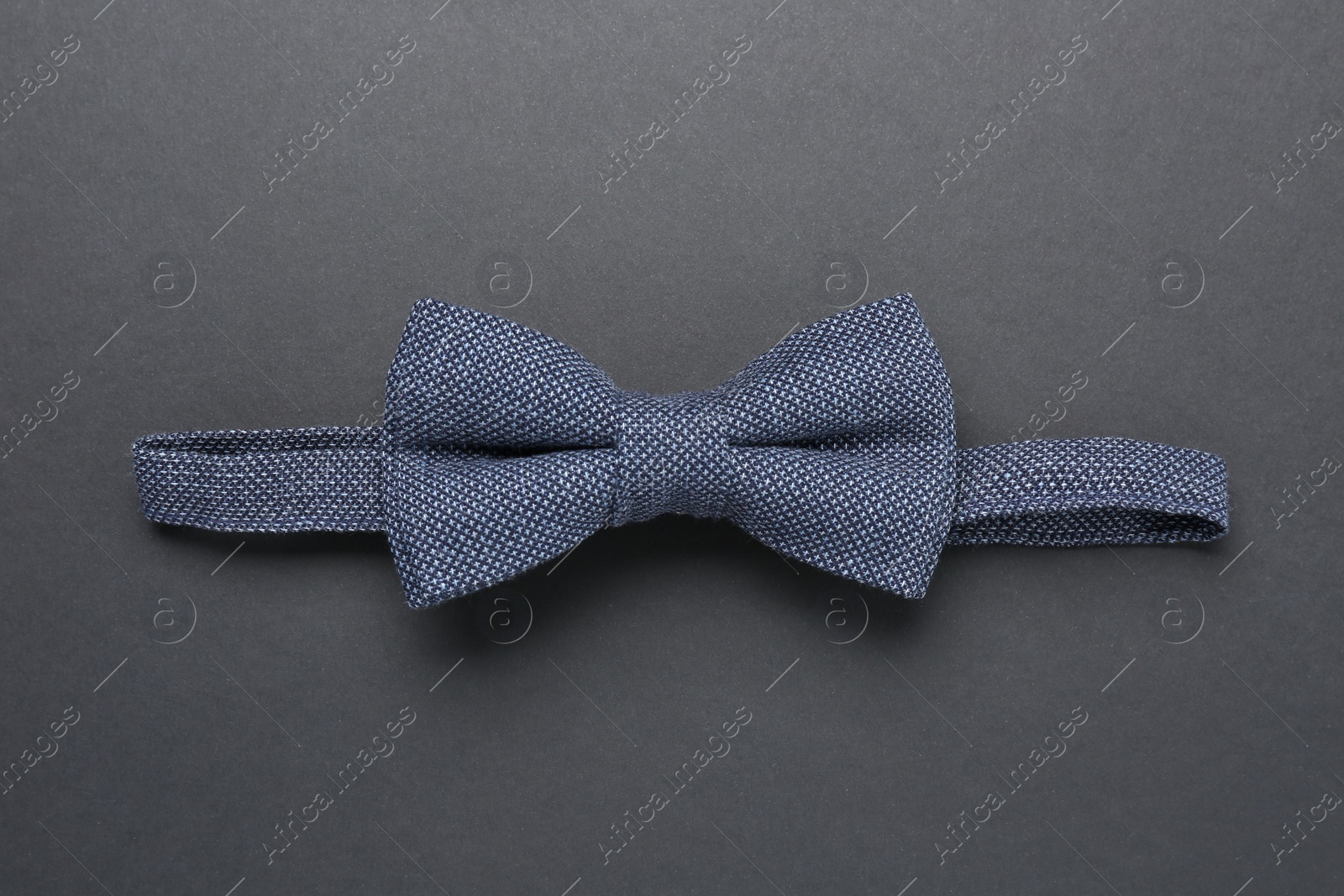 Photo of Stylish blue bow tie on dark background, top view