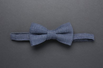 Stylish blue bow tie on dark background, top view