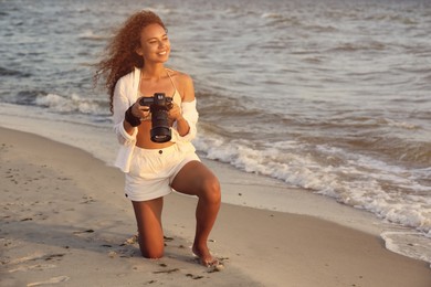 African American photographer with professional camera near sea