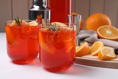 Photo of Aperol spritz cocktail, rosemary and orange slices on white wooden table