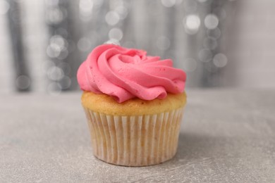 Photo of Delicious cupcake with bright cream on grey table, closeup