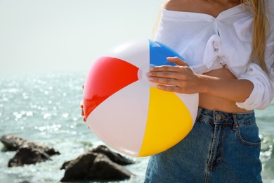 Young woman with inflatable beach ball near sea on sunny day, closeup