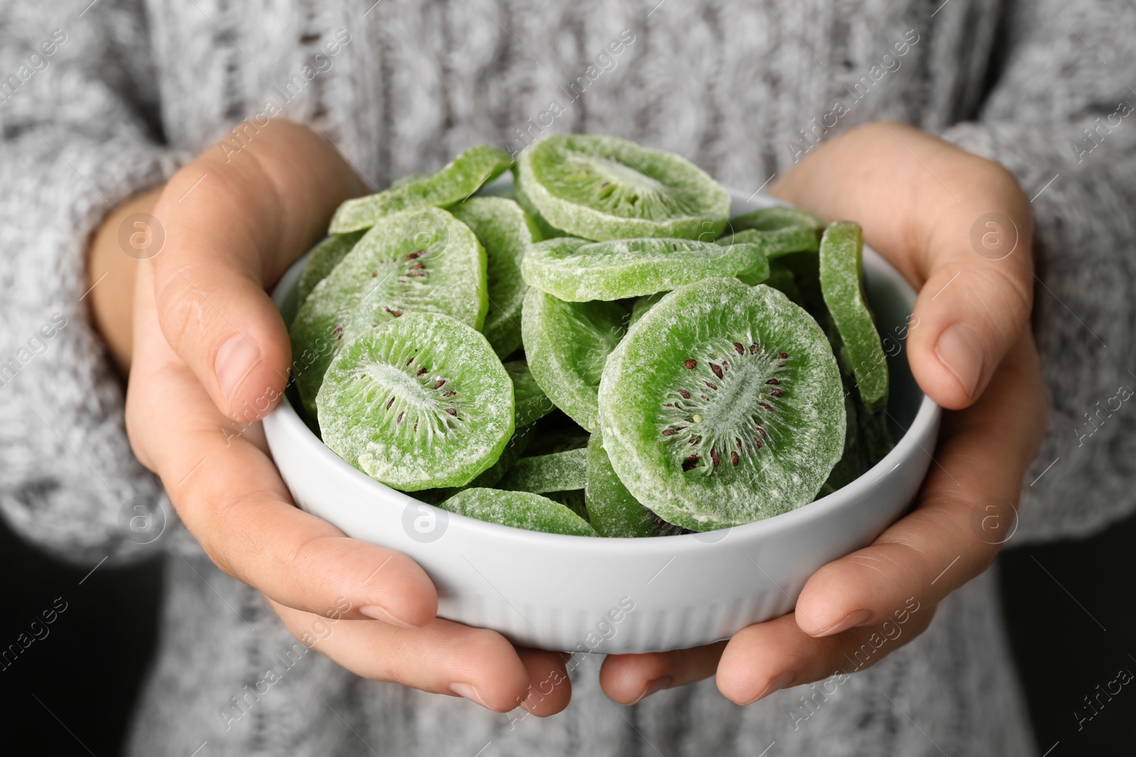 Photo of Woman holding bowl with slices of tasty kiwi, closeup. Dried fruit as healthy food