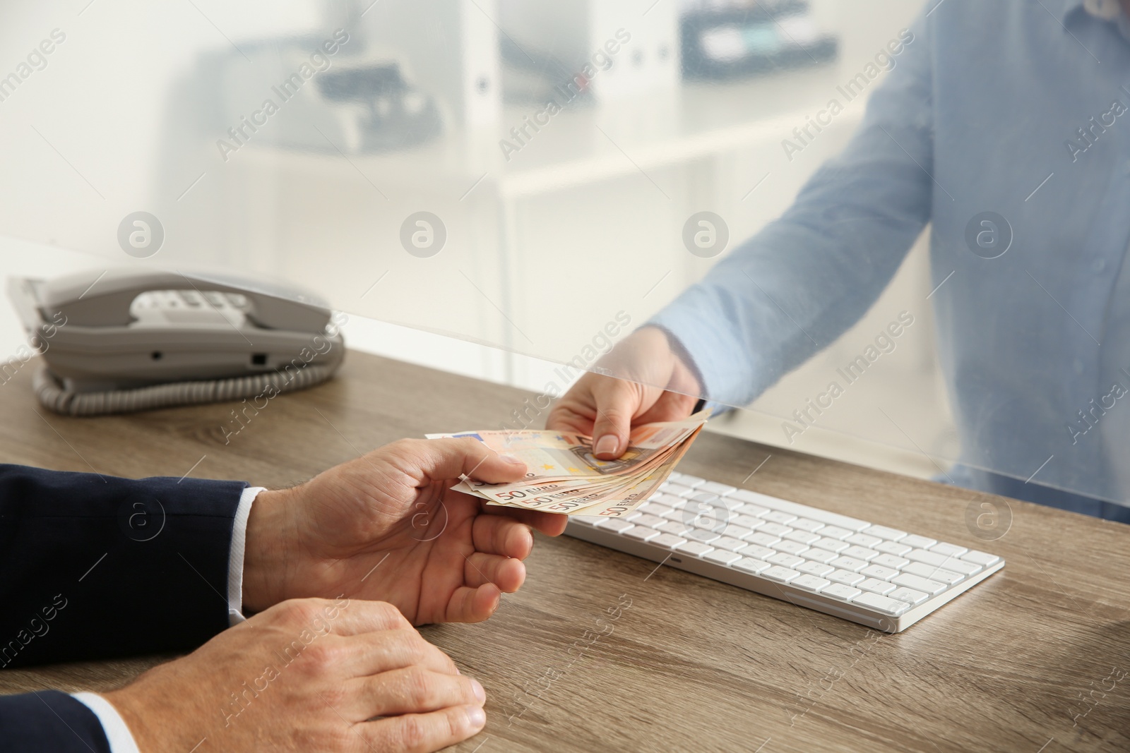 Photo of Man receiving money from teller at cash department window, closeup